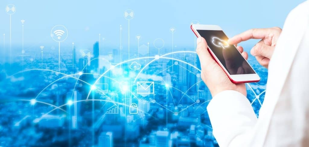 A man in a white coat holding a smart phone in front of a city, showcasing cloud security solutions.
