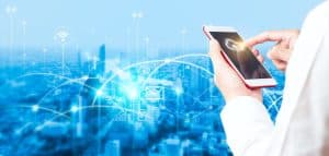 A man in a white coat holding a smart phone in front of a city, showcasing cloud security solutions.