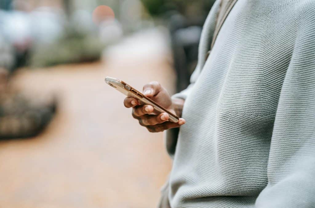 A man is holding a cell phone with data encryption while walking down the street.